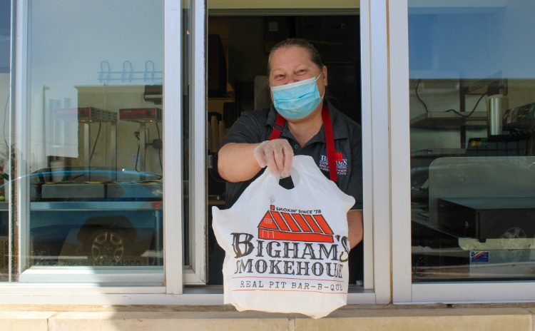 Employee at Bigham's Smokehouse holding a to-go bag